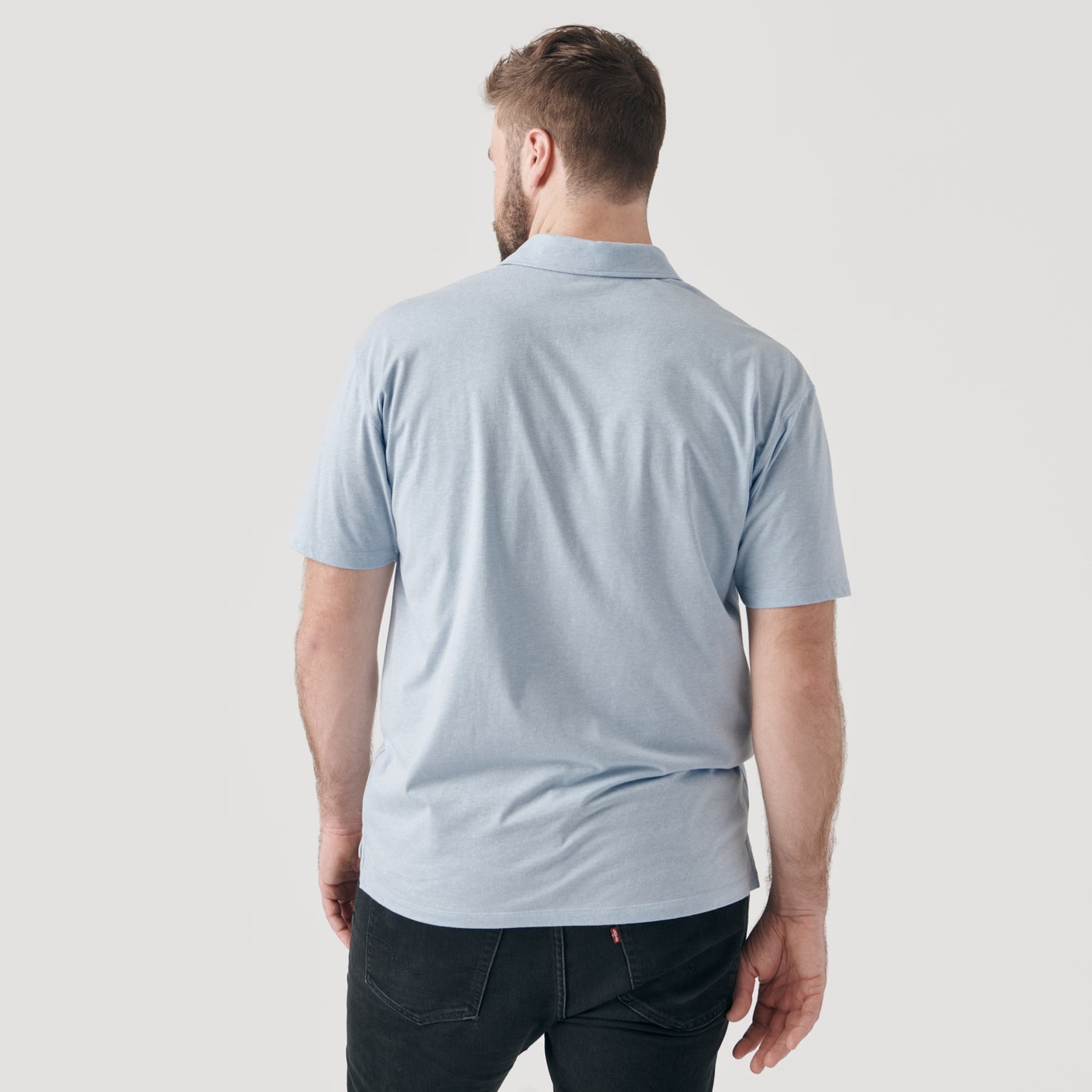 Man wearing Heather Pale Blue Short Sleeve Polo with black jeans.