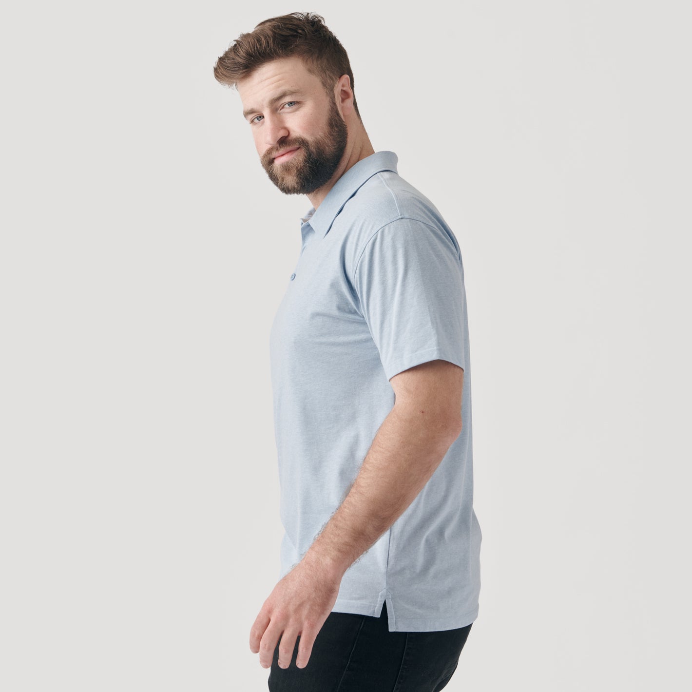 Man in Heather Pale Blue Short Sleeve Polo, side view.