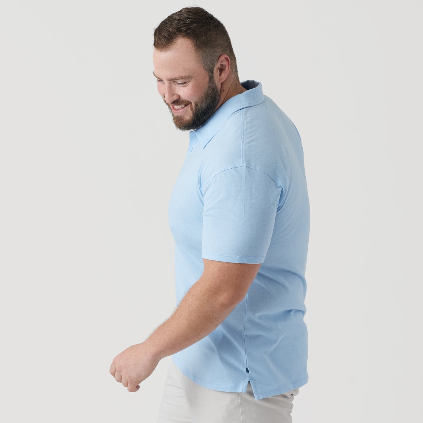 Man wearing Oxford Blue Short Sleeve Polo, smiling, looking down.