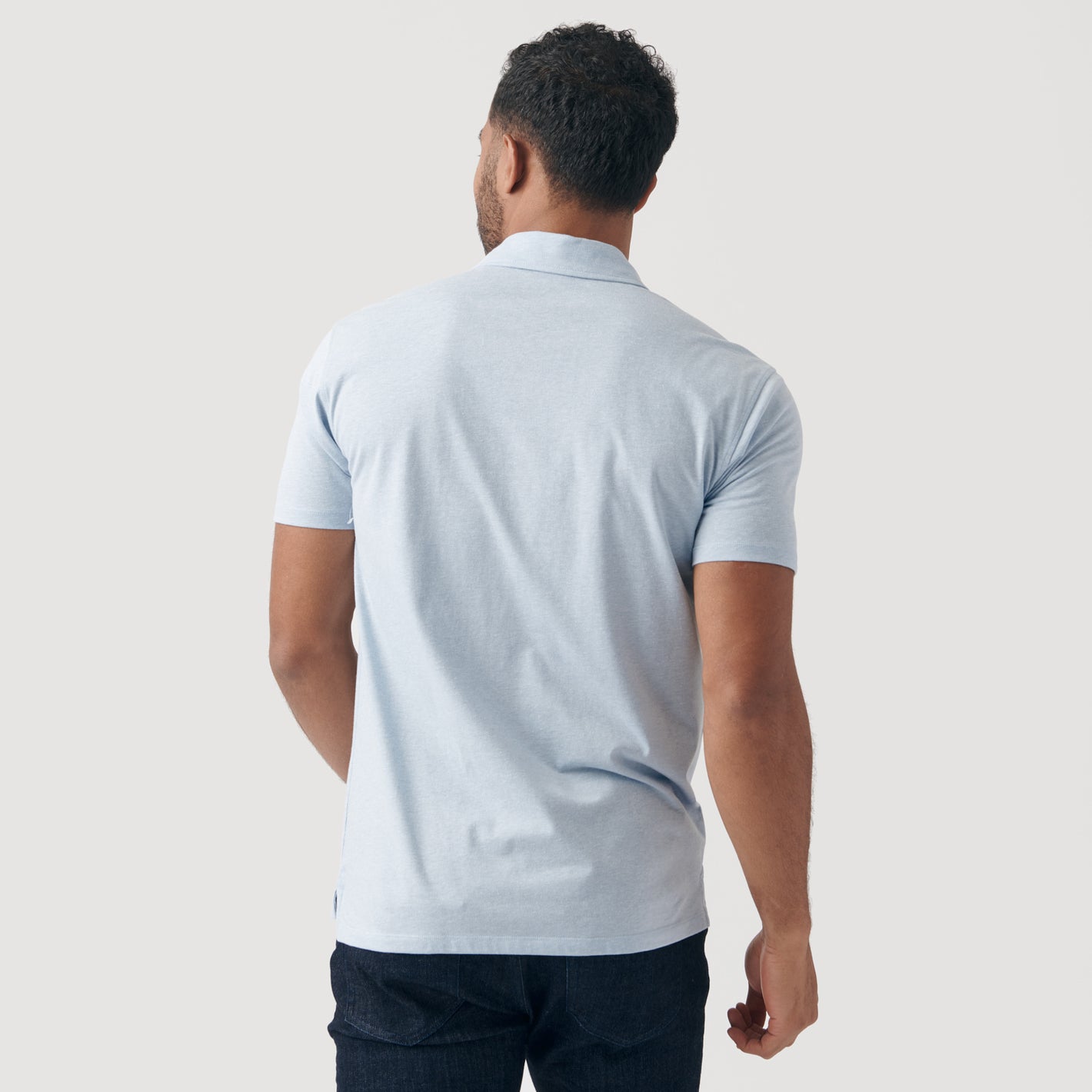 Man in Heather Pale Blue Short Sleeve Polo, back view.