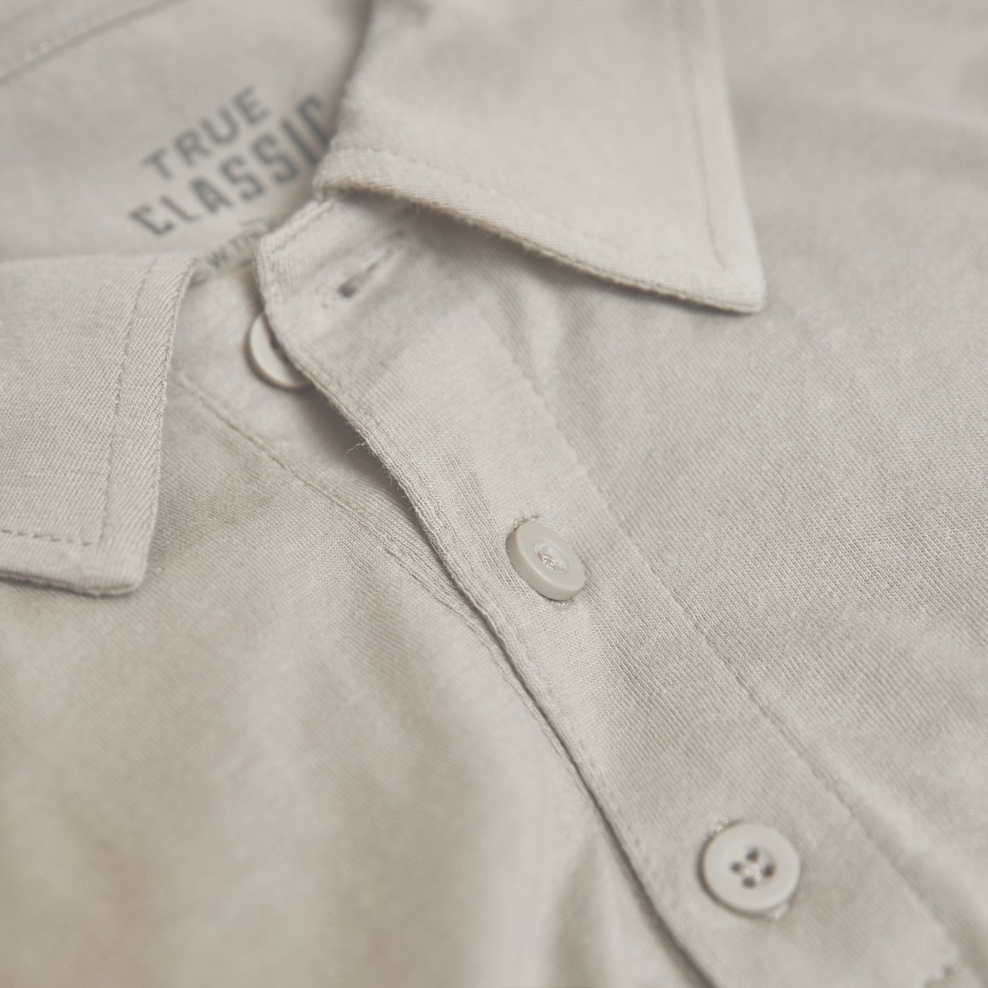 Sandstone Classic Polo close-up showing collar and TRUE CLASSIC label.