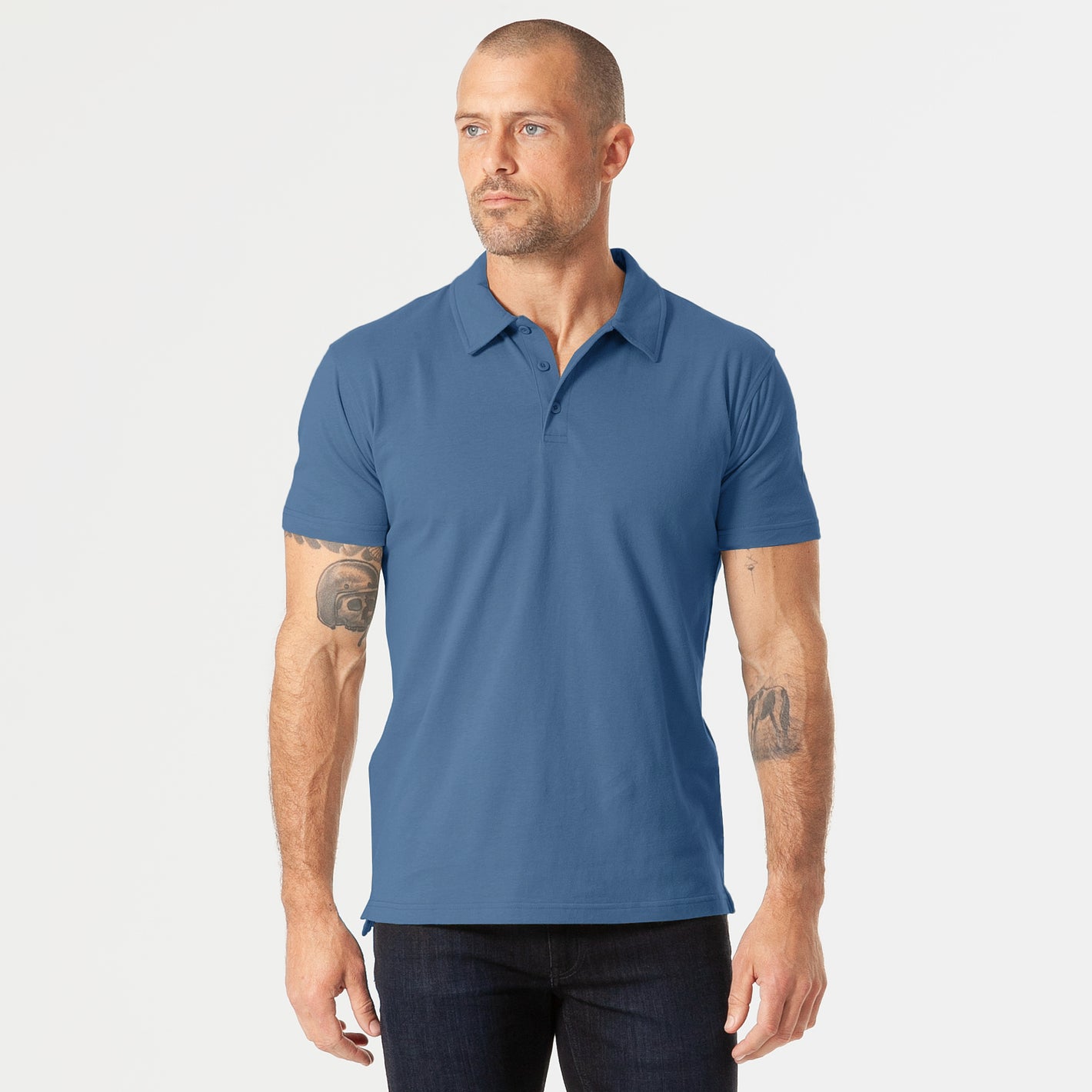 Man models Stone Blue Short Sleeve Polo with dark trousers.