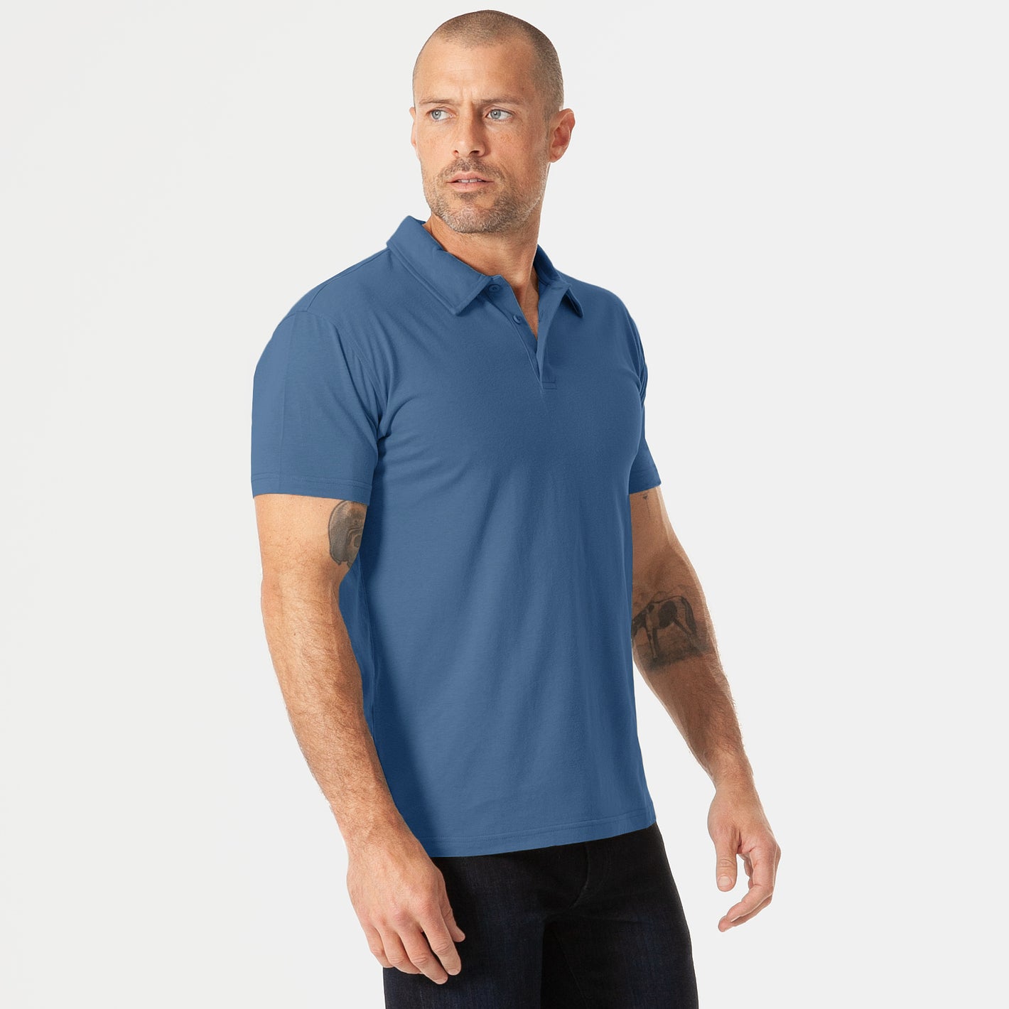 Man wearing Stone Blue Short Sleeve Polo with dark trousers.