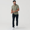 Man wearing Heather Military Green Active Short Sleeve Polo, black trousers, white sneakers.