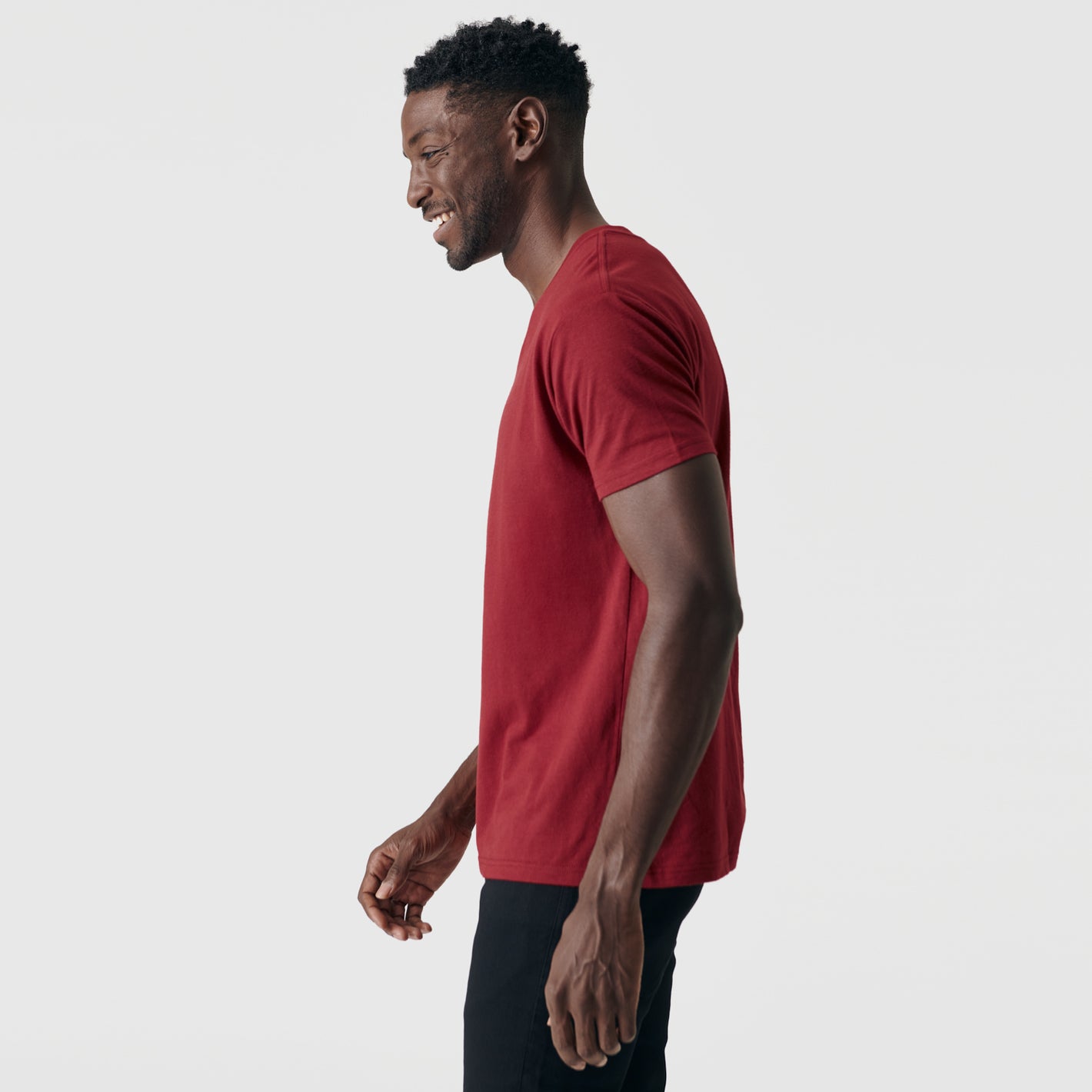 Man wearing Crimson V-Neck Tee, side profile, smiling.