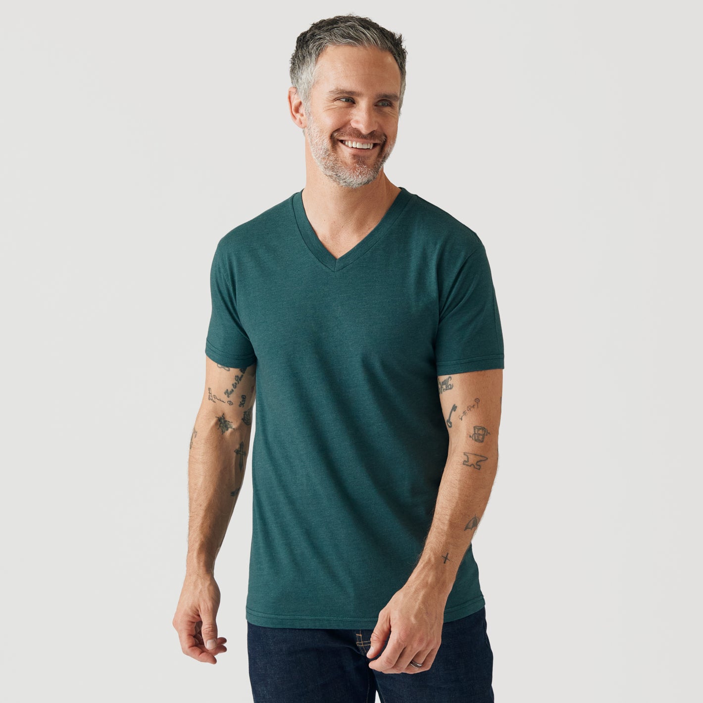 Man wearing Heather Emerald V-Neck Tee and dark pants, smiling.