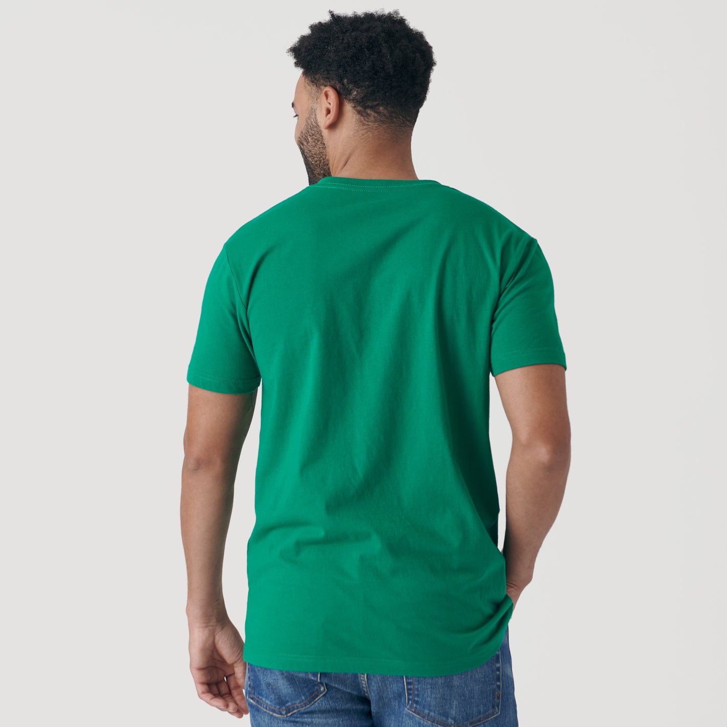 Man wearing Kelly Green V-Neck Tee and blue jeans, back view.