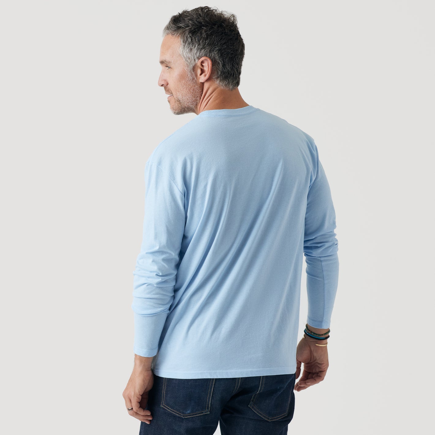 Man wearing Oxford Blue Long Sleeve Crew Neck Tee, side view.