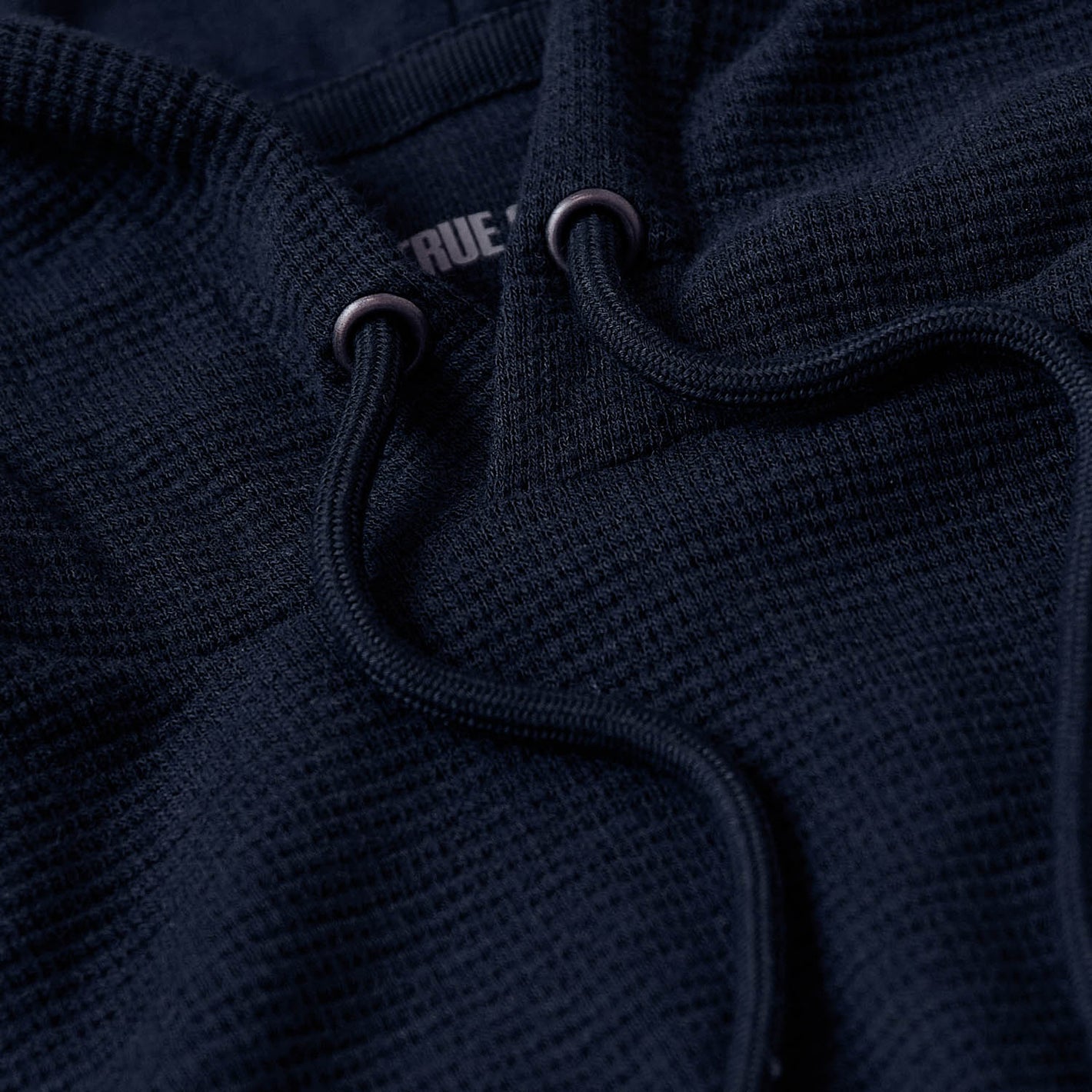 Navy Waffle Hoodie close-up, showing texture and drawcord details.