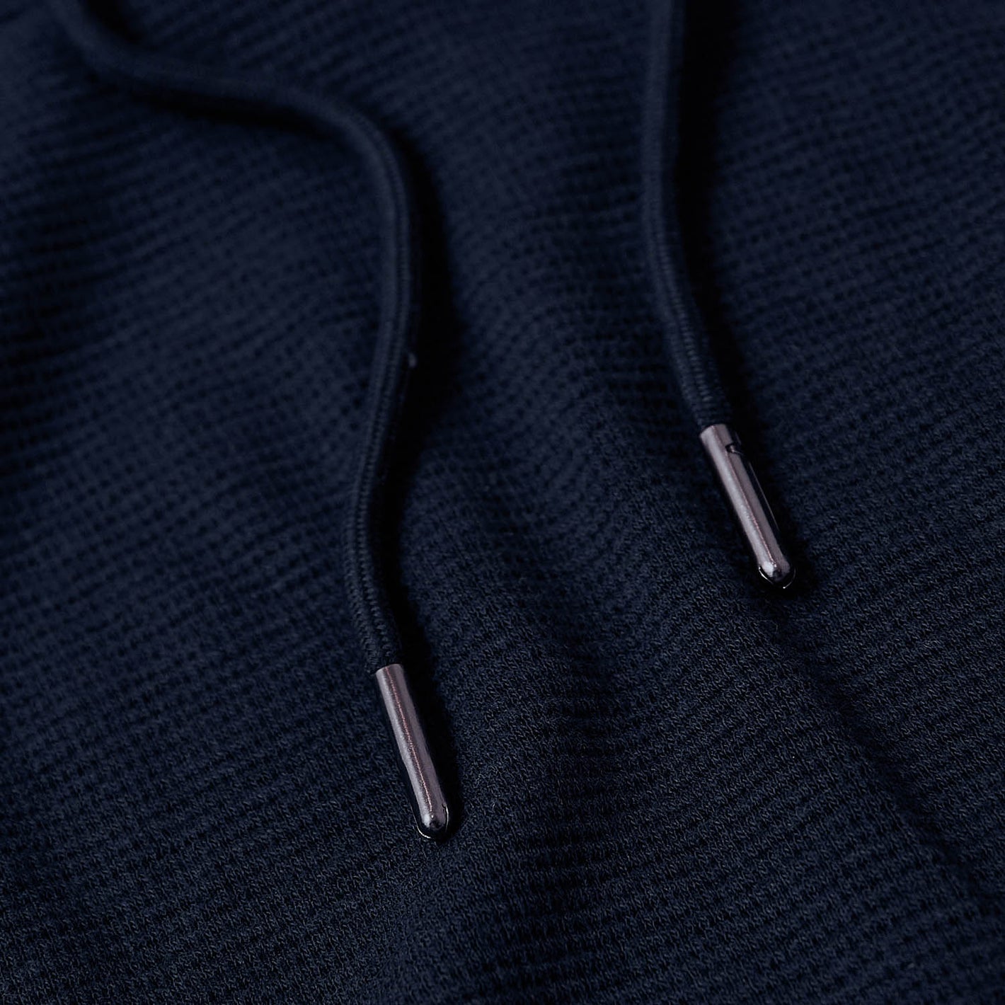 Navy Waffle Hoodie with drawstring aglets, waffle-knit texture.